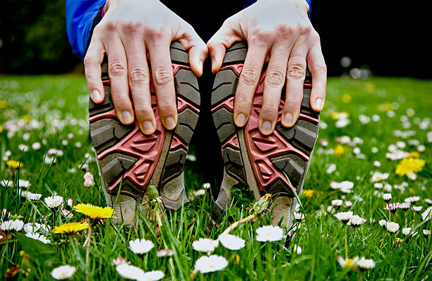 A person stretching holding their trainers stock photo
