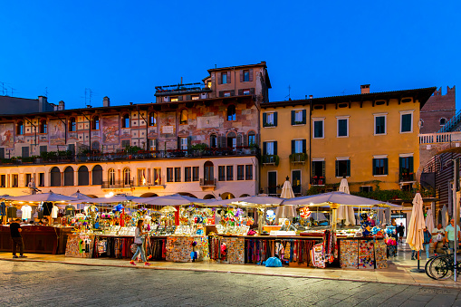 Evening view of vendors selling souvenirs in the Piazza Delle Erbe Market Square in the historic center of Verona, Italy.