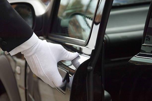 White formal gloved uniformed hand opening car door The white gloved hand of a uniformed doorman / chauffeur opening / closing a black car door. service occupation stock pictures, royalty-free photos & images
