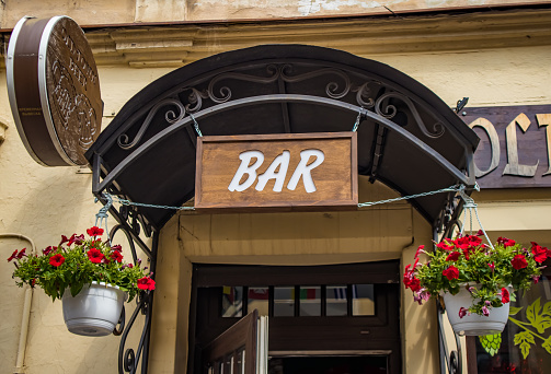 Russia, Vyborg - June 27, 2023: Entrance to a bar decorated with hanging planters with red flowers