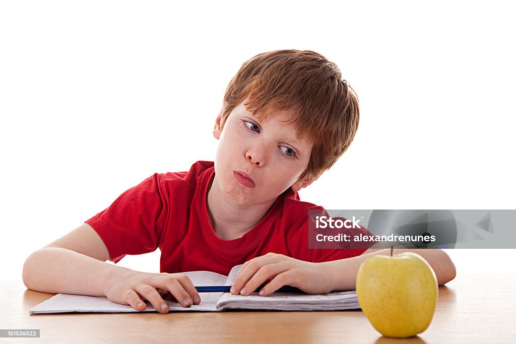 boy studying and distracted with an apple boy studying and distracted with an apple isolated on white background. Studio shot Child Stock Photo