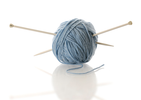 blue yarn with knitting needles with reflection on white background