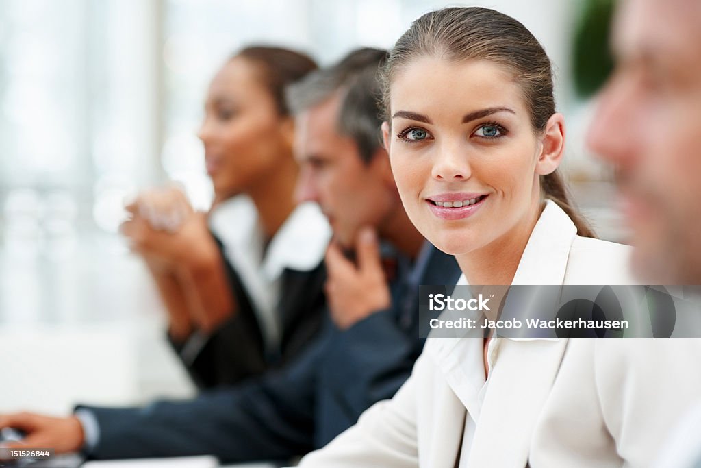 Fiducioso donna d'affari seduto con i suoi colleghi - Foto stock royalty-free di Amministratore Delegato