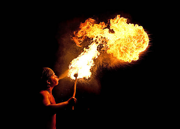 young fireblower y fuego sobre fondo negro - fire eater fire performance circus performer fotografías e imágenes de stock