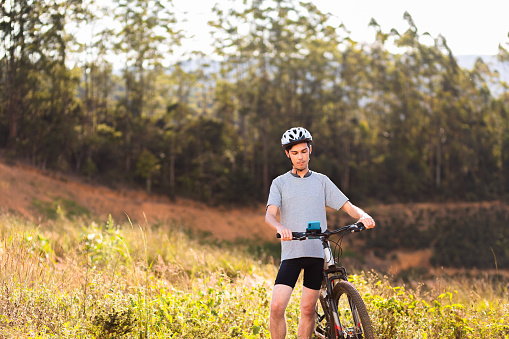 Athlete with his mountain bike on the trail with trees in the background