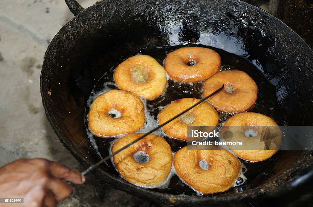 Frying donuts in big iron wok Cooking Stock Photo