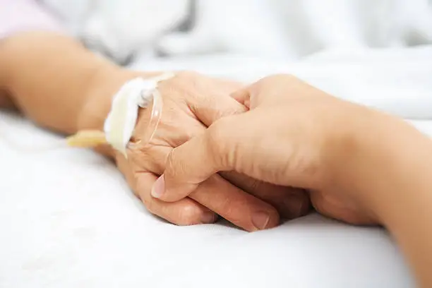 Daughter holding her mother hand, that injected with IV  in hospital