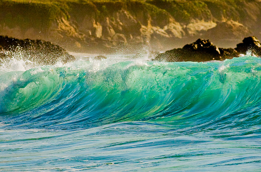 Aerial drone overhead view of huge beach and dynamic sandy, rocky coastline with large crashing foamy waves over turquoise water.