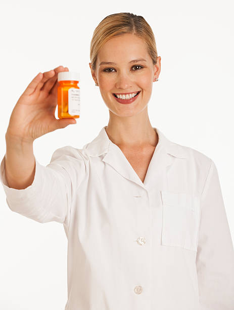 female pharmacist holding up bottle of pills stock photo