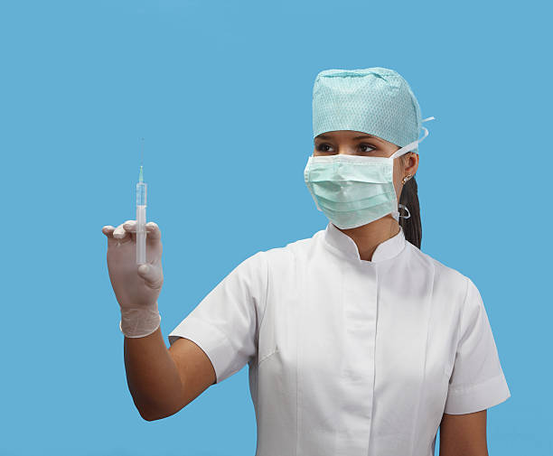 Female nurse holding a syringe isolated against a blue background.