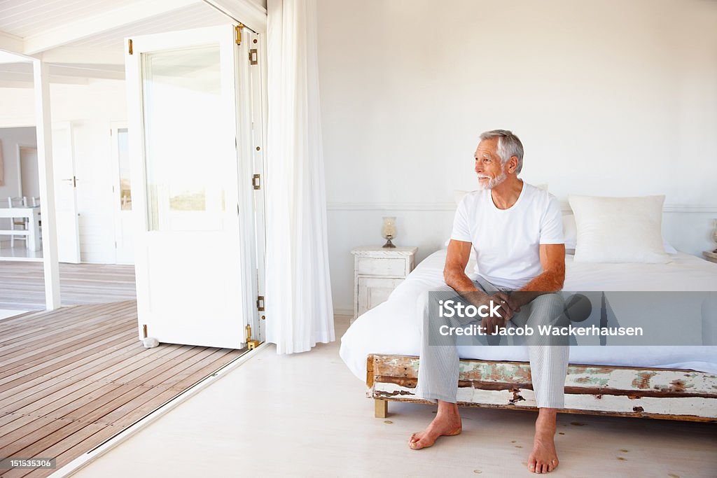 Contemplativo senior hombre sentado en la cama - Foto de stock de Cama libre de derechos