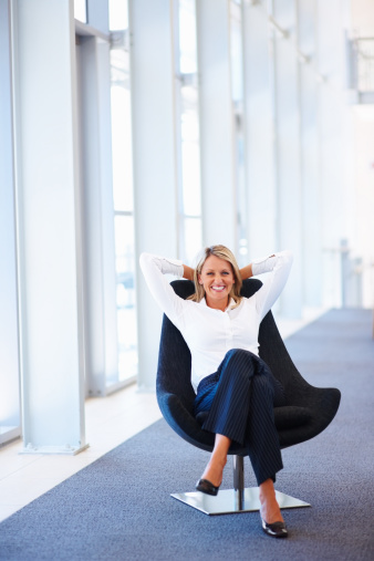 Happy mature businesswoman relaxing on office chair