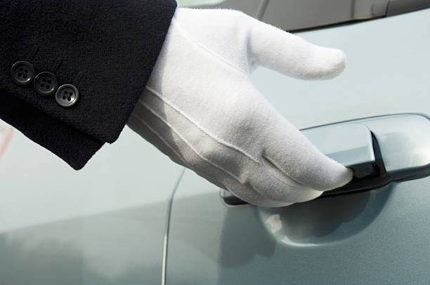 istock White formal gloved uniformed hand opening car door 151536120