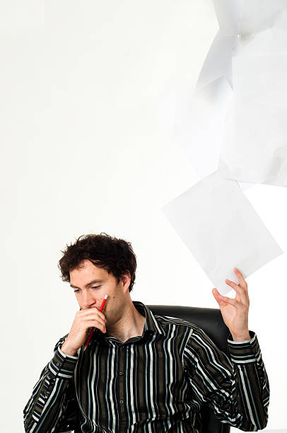 istock Man sitting at desk throwing up paperwork 151538592
