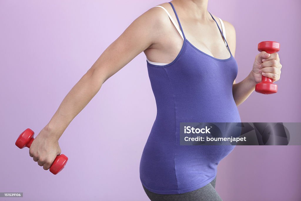 Pregnant woman exercising with handheld weights Active pregnant woman. Abdomen Stock Photo