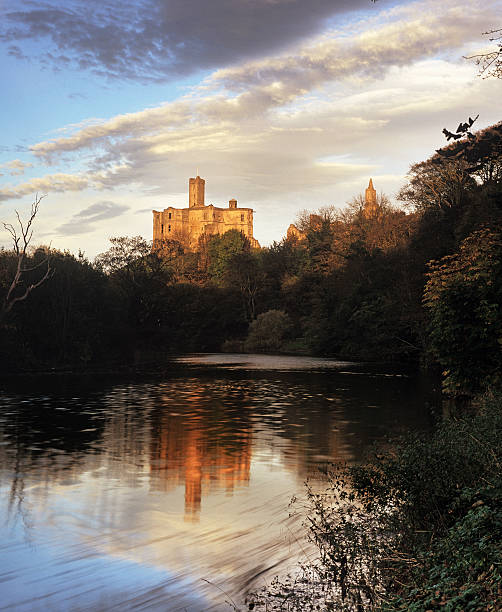Warkworth Castle reflected in the River Coquet, in evening sunlight