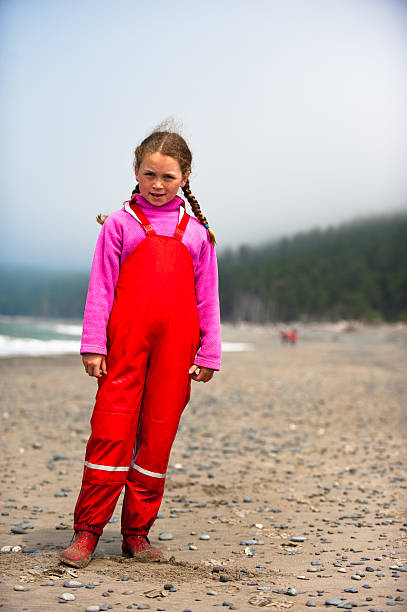 young girl in red rain clothes on ocean beach stock photo