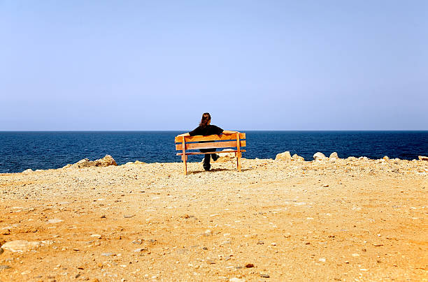istock Woman sits on a bench at coast 151542314