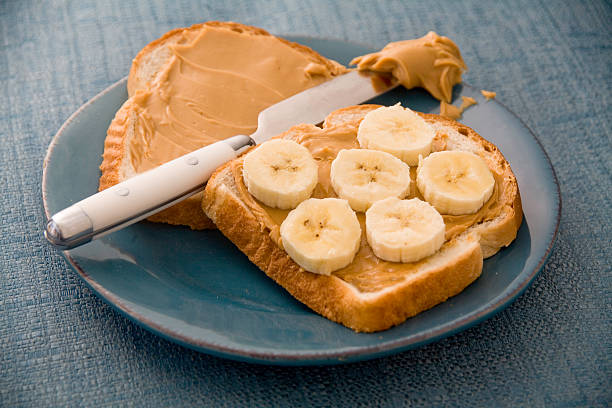 A peanut butter and banana sandwich on a blue plate and placemat. Ready to be consumed.