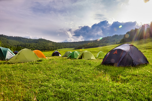 Tourist tent in the camp among the meadows in the mountains. Outdoor camping with beautiful sunshine in the morning