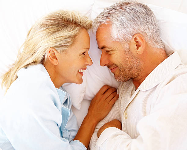 счастливая зрелая пара на кровать - couple affectionate relaxation high angle view стоковые фото и изображения