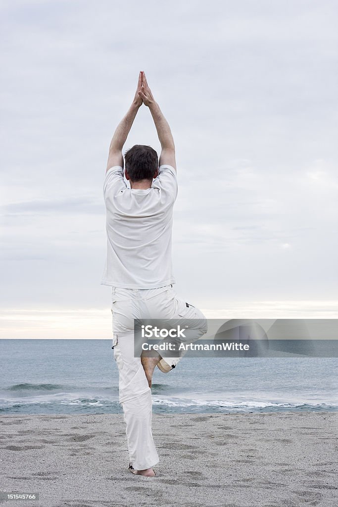 Man doing yoga on beach Man in white cloths doing yoga on a beach 30-39 Years Stock Photo