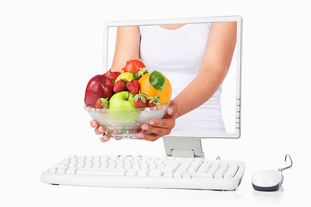 istock Female hand holding fruits coming out from computer screen 151545983