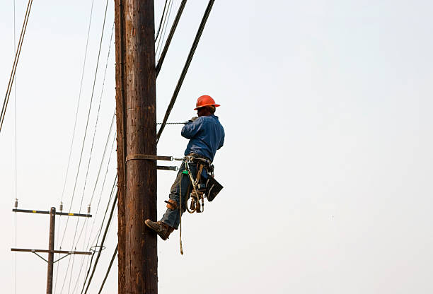 Utility worker drilling hole while suspended in air Utility worker telephone pole stock pictures, royalty-free photos & images