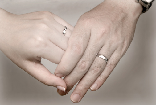 A couple holding hands with wedding band on finger
