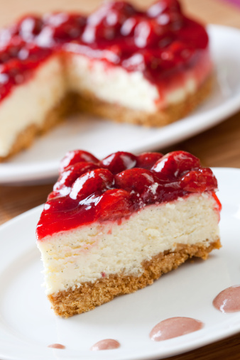 Slice of delicious strawberry cheese cake with a cake in the background