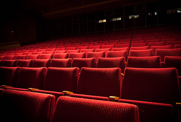 Empty theatre with red seats in low light auditorium seat stock pictures, royalty-free photos & images