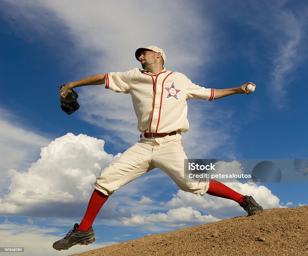 Baseball Pitcher on Mound Baseball pitcher on pitcher's mound at full stretch about to release the ball. Set against a bright blue sky. Horiztonally framed shot. Baseball Pitcher Stock Photo