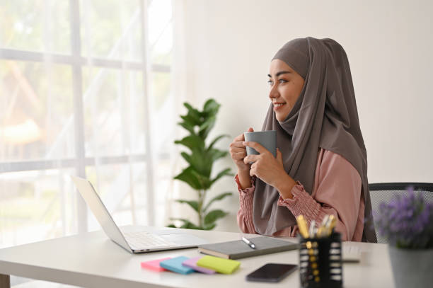 istock Young charming Muslim businesswoman having a coffee while working with laptop 1515493335