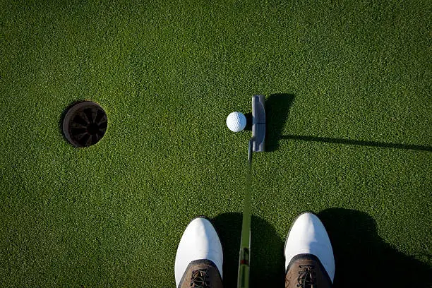 A golfer about to tap in a easy putt.