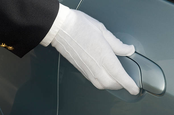 White gloved hand of chauffeur / doorman on car door The white gloved uniformed hand of a doorman or chauffeur on the door handle of a silver car - close up. door attendant photos stock pictures, royalty-free photos & images