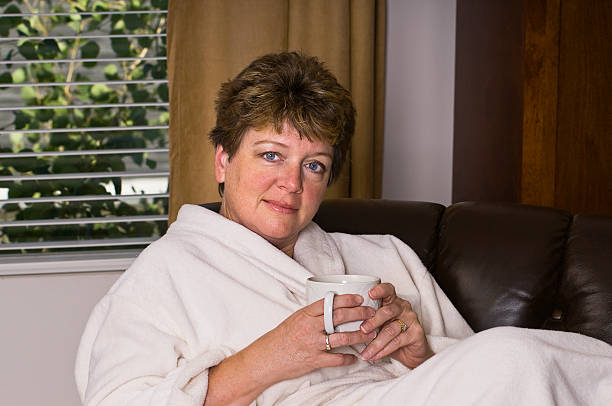 Woman in white bathrobe drinking coffee stock photo