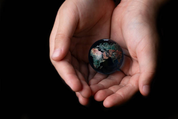 istock Glass symbolic globe in children's palms on a black background 1515527233