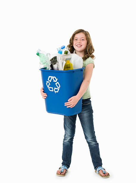 Pretty young girl holding blue recycle bin on white background 8 year old girl with long brown hair smiling to camera and holding a blue recycling container filled with domestic recyclable materials recycle symbol cut out stock pictures, royalty-free photos & images
