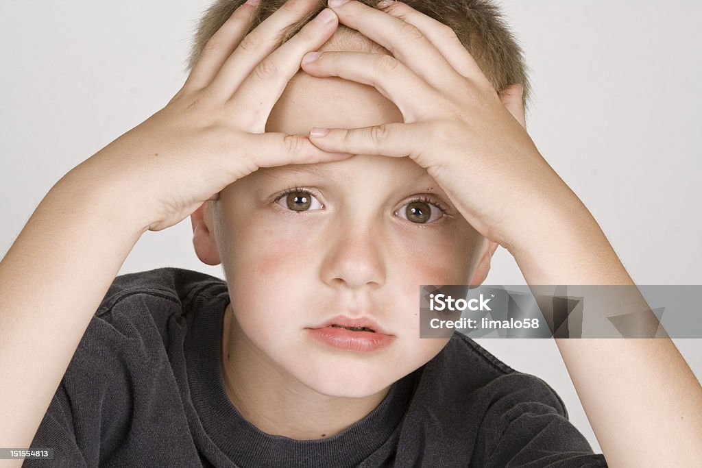 Frustrated little boy Young boy with his head in his hands with a frustrated look on his face. Boys Stock Photo