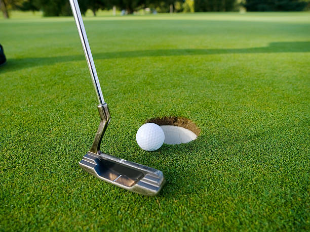 A person playing golf hitting the ball in the hole putting on the golf green, golf club has place for logo putting stock pictures, royalty-free photos & images