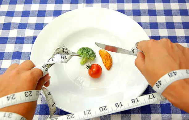 Hands restricted by a tape measure while trying to eat a small meal