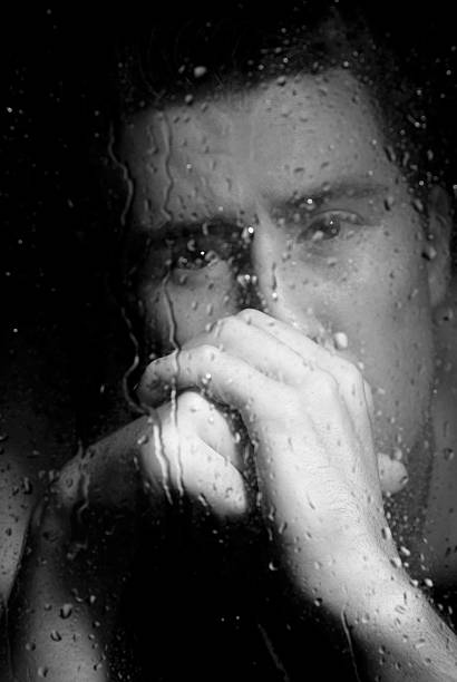istock Depressed man looking through the window at night 151557988