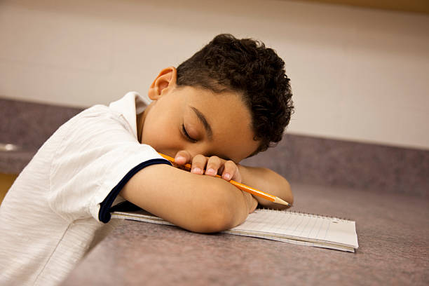 Jovem estudante elementar dormir na turma. - fotografia de stock