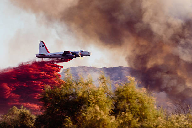 Wildfire Air Tanker The balance within this image helps to show the major elements. The trees centered in the foreground are the main concern. The smoke signals the threat attacking from the right. Balanced with the retardant drop coming into the scene from the left. military tanker airplane photos stock pictures, royalty-free photos & images