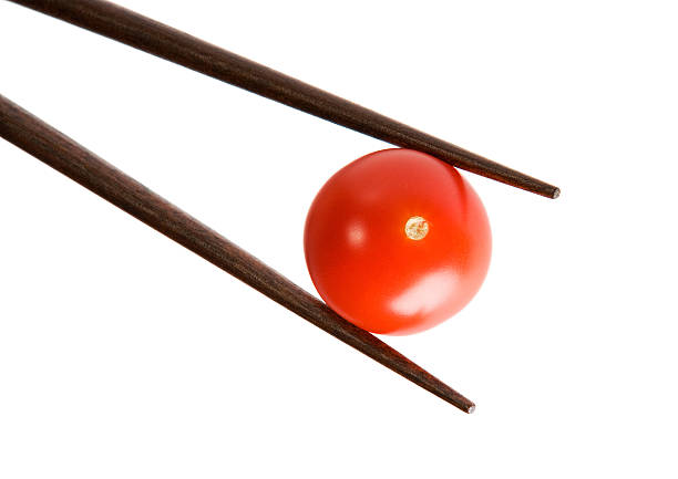 Bamboo chopsticks and cherry tomato on white background stock photo