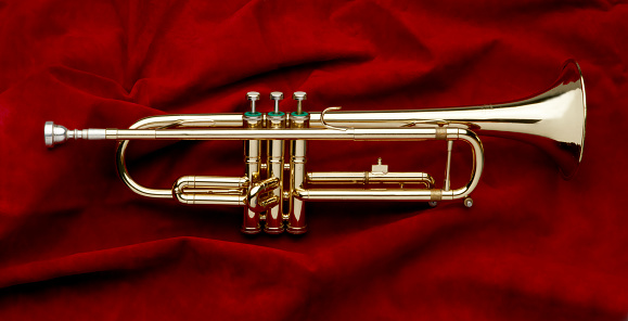 Full shot of shiny trumpet on red suede background