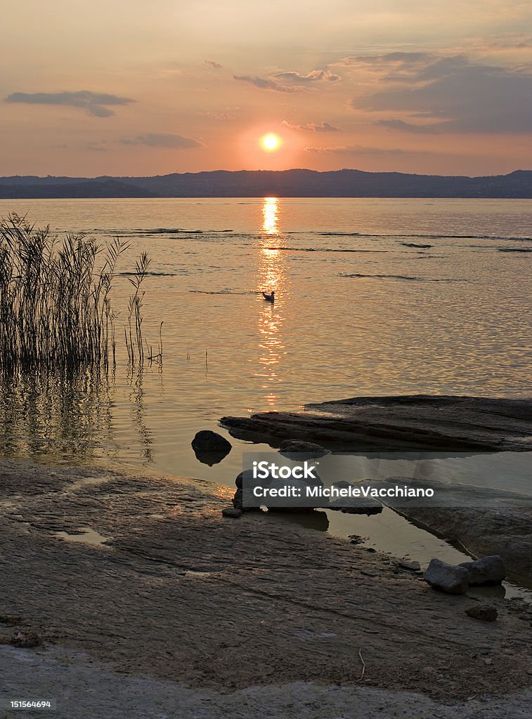 Lake Garda (Sirmione, Italy): sunset Italy. Region of Lombardy. Province of Brescia. City of Sirmione (more like this: http://www.istockphoto.com/file_search.phpaction=file&lightboxID=7347922). Sirmione is an ancient little town located at the end of a long, narrow peninsula jutting into the Lake Garda, the Italy's biggest lake. This is a richly historical resort, with the imposing Scaligeri Castle standing at the entrance to the medieval town where narrow streets are lined with cafAs, shops, villas and churches. The famous thermal waters of Sirmione are rich in sodium, bromine and iodine. The Roman poet Catullus, a contemporary of Julius Caesar, was born there. Today Sirmione still keeps many remains of its ancient history. First among these is the grandiose Roman villa known as ""Grotte di Catullo"", dating back to the beginning of the 1st century. Near the ""Grotte di Catullo"" there is the Lombard church of San Pietro in Mavino, containing medieval frescos. The ""Rocca Scaligera"" was built in Middle Age on the remains of an ancient Roman fortification. Brescia Stock Photo