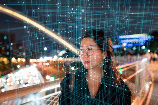 Woman walking on pedestrian bridge in city at night, smart city, virtual reality, metaverse concept