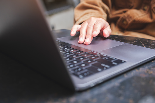 Closeup image of a woman working and touching on laptop computer touchpad