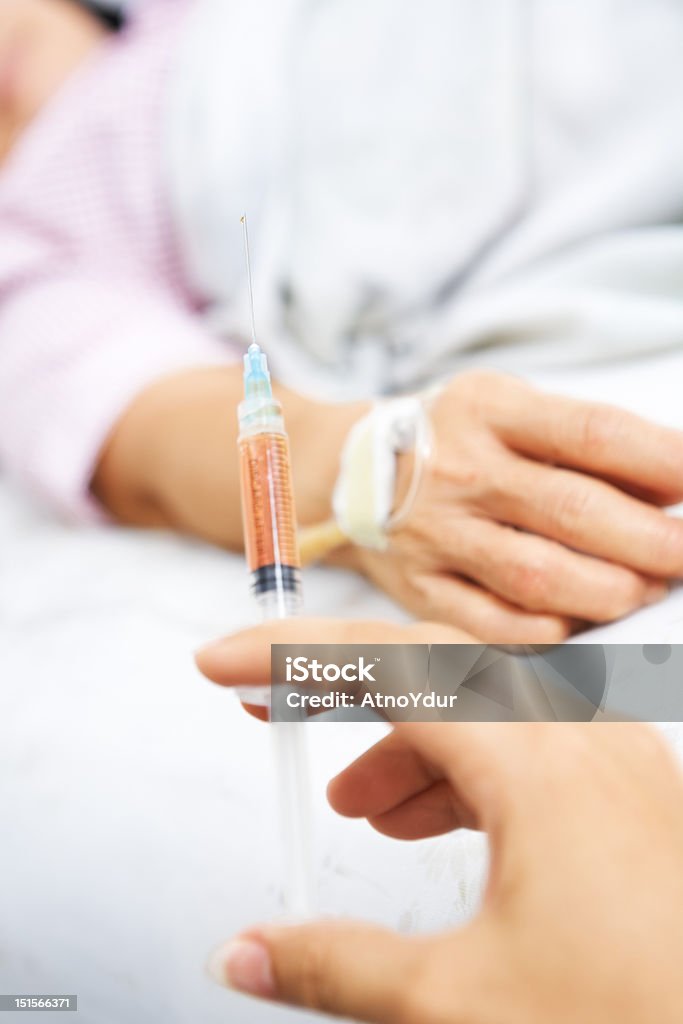 Mano agarrando inyección con el paciente en el fondo - Foto de stock de Adulto libre de derechos